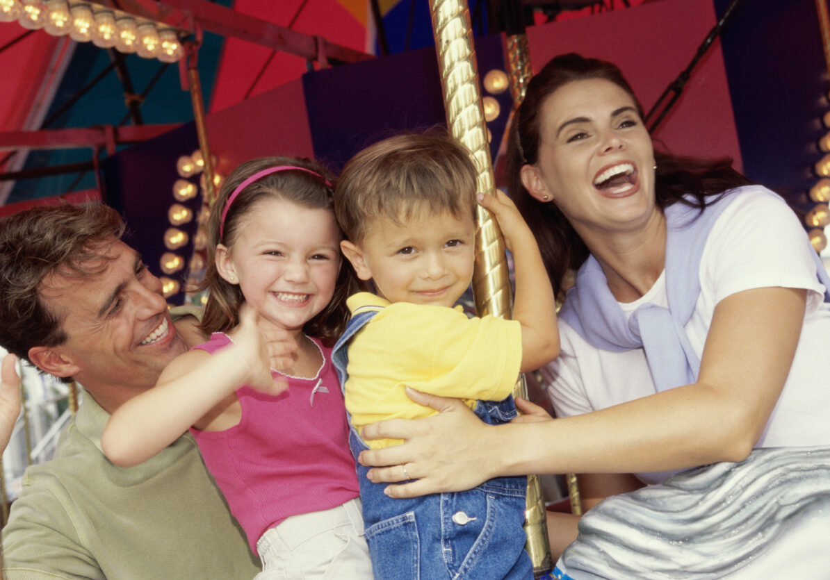 Young couple sitting on a carousel with their son and daughter